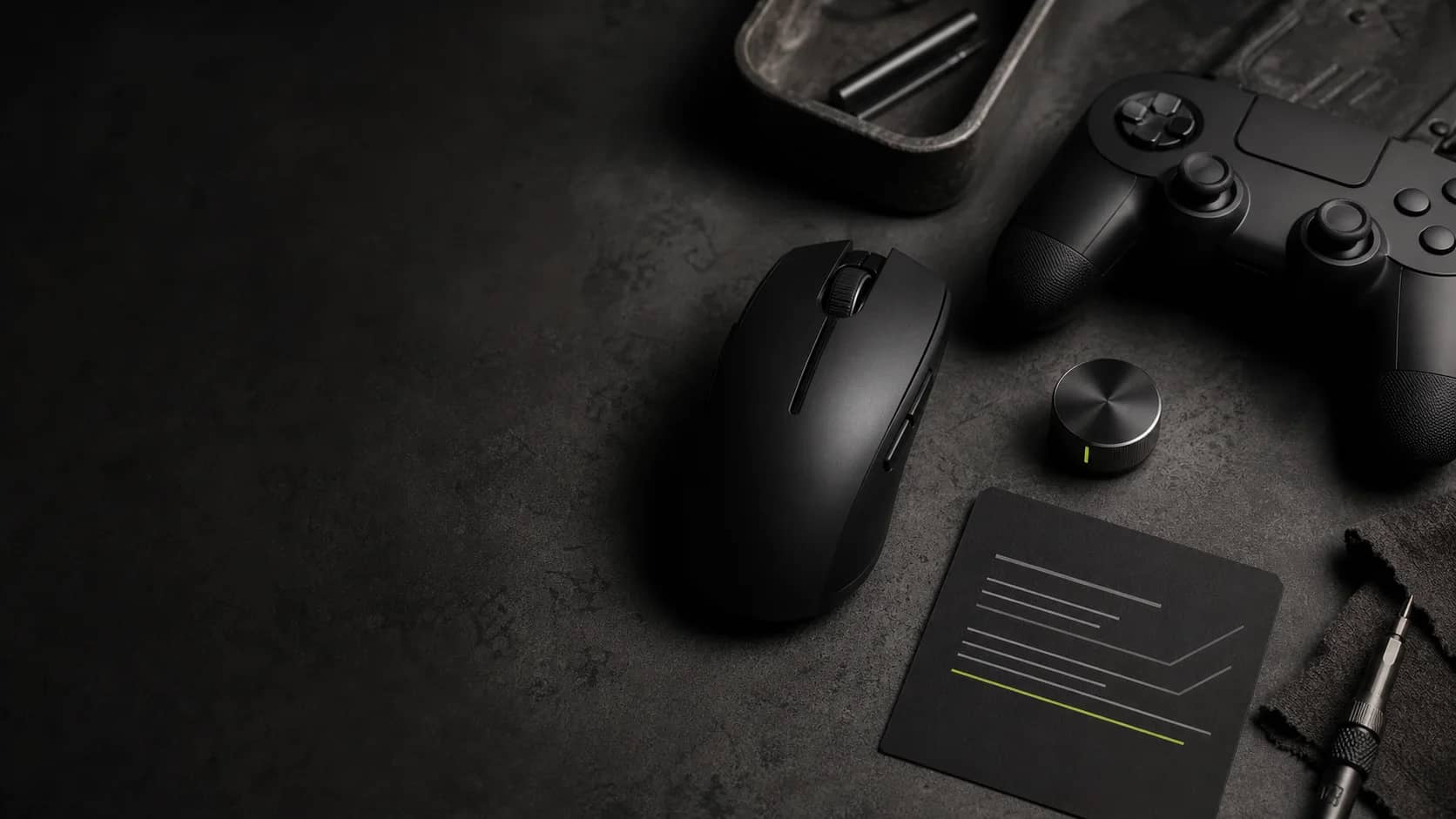 A gaming mouse, controller, and setup card on a dark workbench