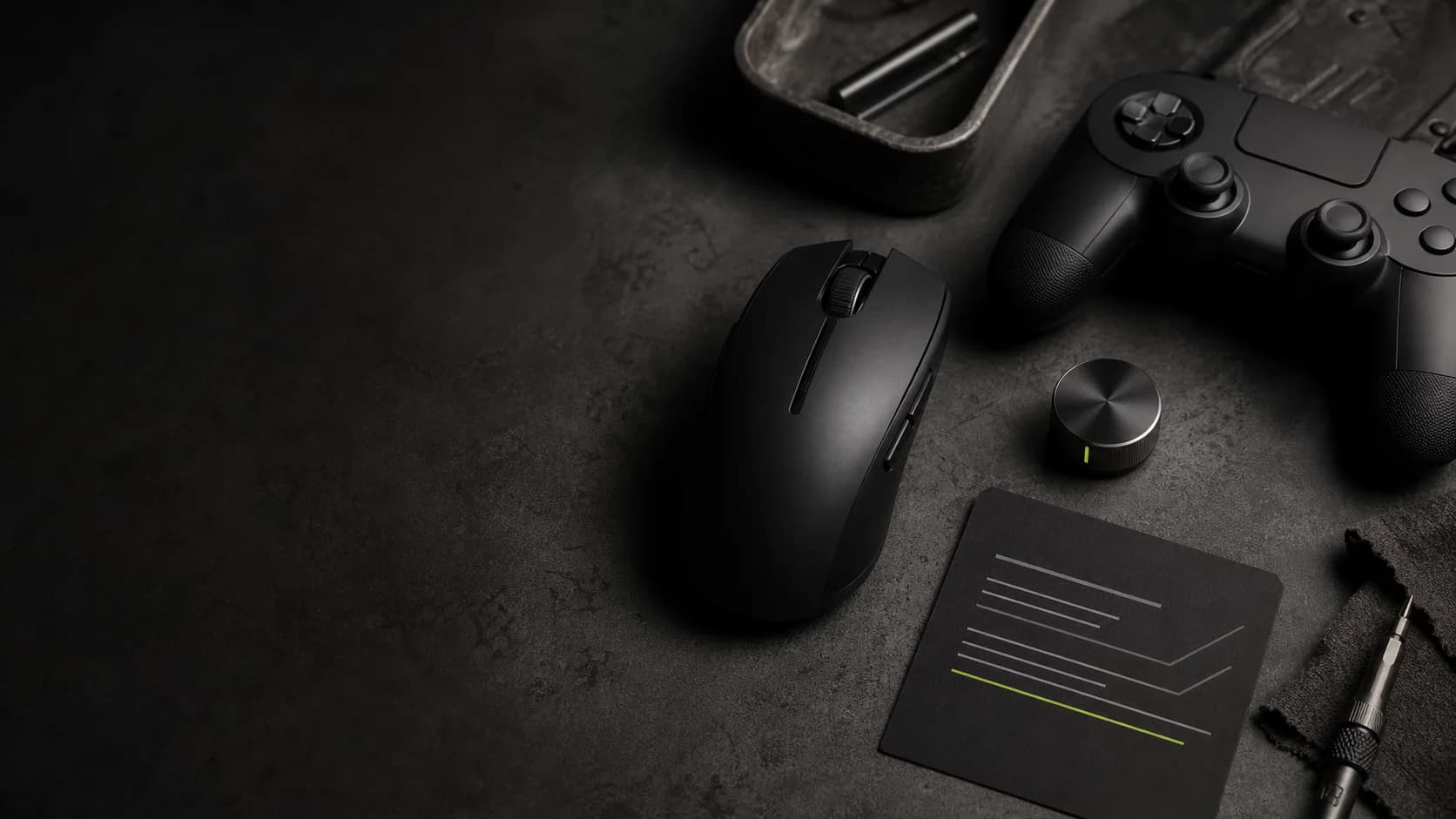 A gaming mouse, controller, and setup card on a dark workbench